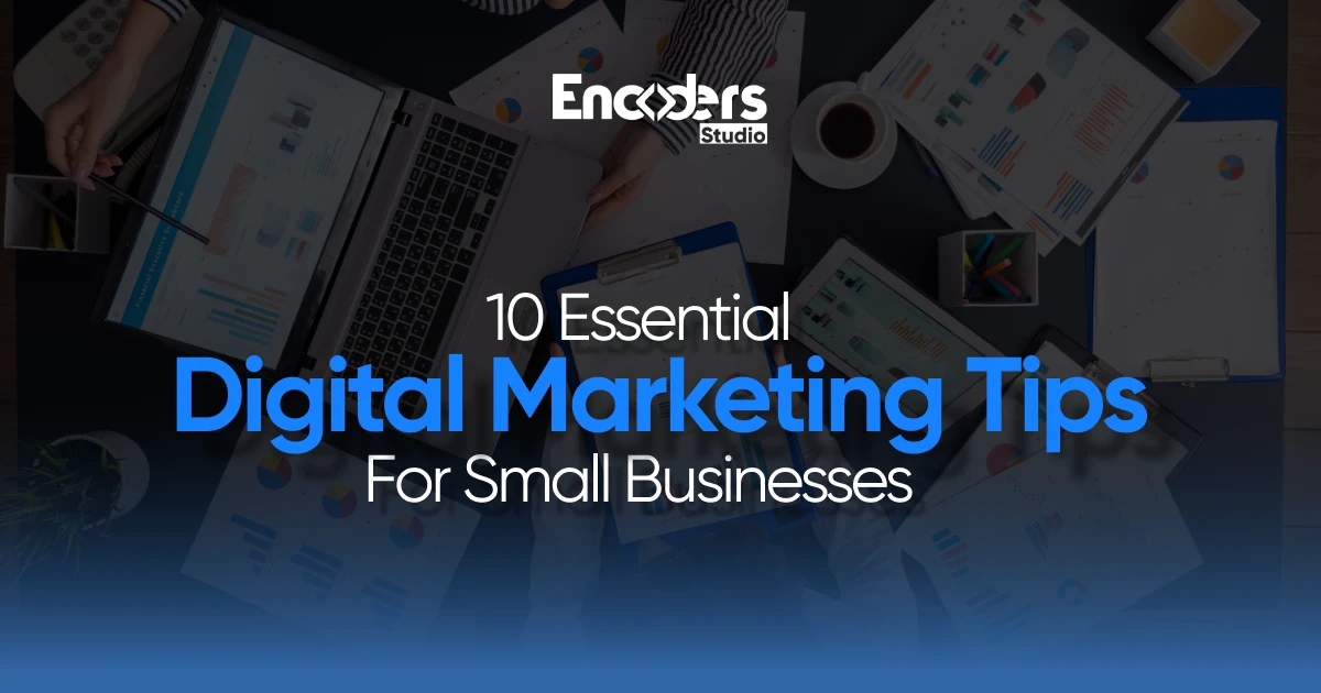 An overhead view of a busy desk with laptops, a tablet, charts, and coffee, with the title "10 Essential Digital Marketing Tips For Small Businesses."